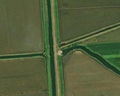 3/4 Station de pompage (man_made=pumping_station) à proximité d'un cour d'eau et d'un chemin (imagerie satellite Maxar).