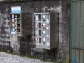grave-candle vending machines on the wall of a graveyard in Tolmin