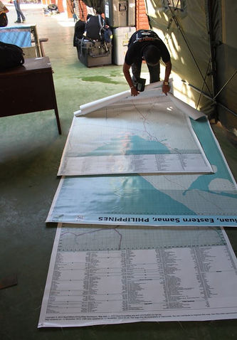 three large poster maps of Tacloban, Guiuan and Ormoc on the floor for post-typhoon aid
