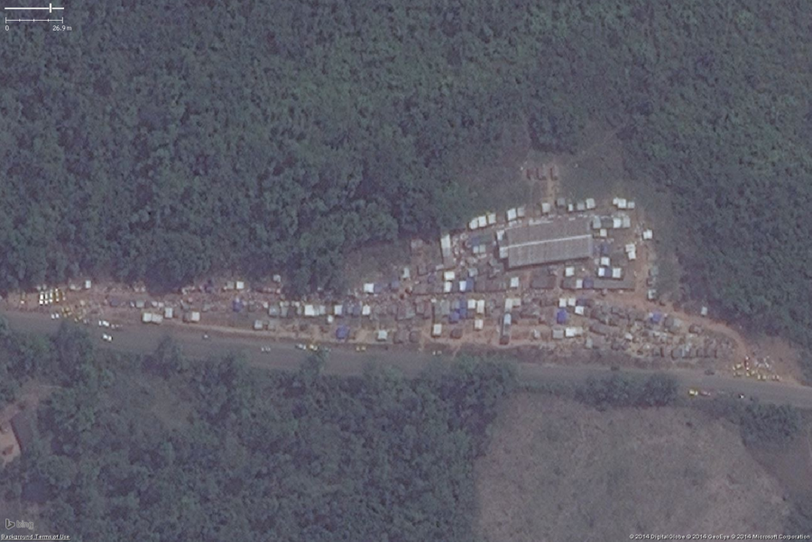 A likely marketplace in West Africa. The key features are the small buildings tightly packed, this one probably has tents for stalls as well. This is another roadside market along a major highway=primary just outside a large town. You can see a number of cars parked along the road and what is probably people along the main market area. The collection of small buildings and tents should be tagged amenity=marketplace and fixme=confirm (unless you have first hand knowledge it is a marketplace).